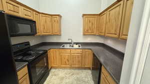 Kitchen with black appliances, a sink, and dark countertops