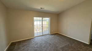 Empty room featuring dark colored carpet and baseboards