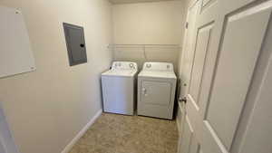 Laundry area featuring electric panel, separate washer and dryer, baseboards, and light tile patterned floors