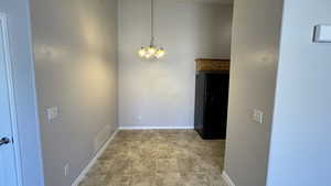 Unfurnished dining area featuring a chandelier and baseboards
