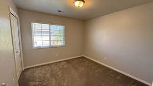 Spare room featuring dark carpet and baseboards