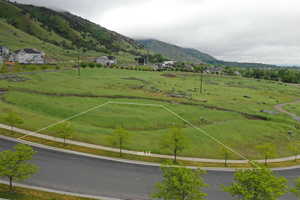 Aerial view of sparsely populated area featuring a pastoral area and a mountainous background