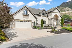 French country inspired facade with driveway, a mountain view, and stucco siding