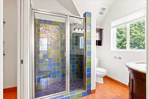 Full bathroom with toilet, vanity, vaulted ceiling, a shower stall, and tile patterned floors