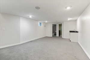 Finished basement featuring light carpet, baseboards and sink.