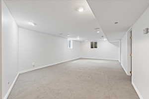 Basement with light colored carpet and baseboards