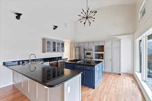 Kitchen featuring a peninsula, stainless steel appliances, light wood-type flooring, blue cabinetry, and a sink