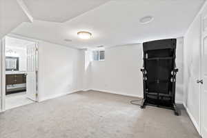 Workout area with a sink, baseboards, a textured ceiling, and light colored carpet