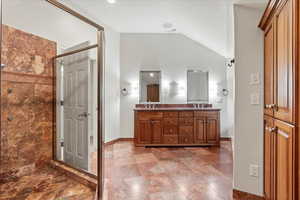 Bathroom featuring tub, double vanity, a shower stall, baseboards, and vaulted ceiling