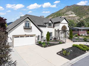 French country home with roof with mountain views, concrete driveway, and stucco siding
