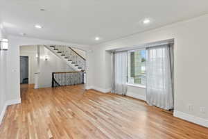 Unfurnished room with crown molding, light wood-style flooring, and baseboards