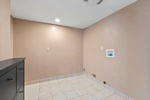 Washroom featuring light tile patterned floors, gas dryer hookup, washer hookup, baseboards, and cabinet space