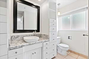 Bathroom with toilet, tile patterned floors, and vanity