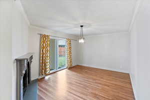 Unfurnished living room with baseboards, crown molding, and light wood-style floors