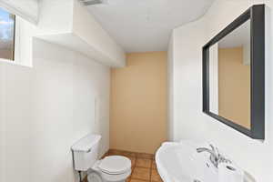 Half bathroom with visible vents, a sink, toilet, and tile patterned floors