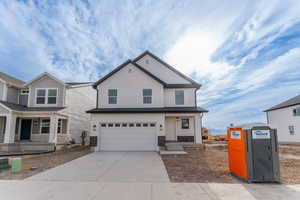 View of front facade featuring covered porch, stone siding, concrete driveway, and an attached garage