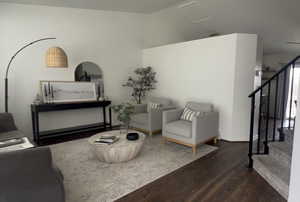 Living area with stairs, dark wood-type flooring, and vaulted ceiling