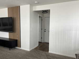 Interior space with baseboards, dark carpet, and a textured ceiling