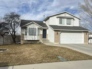 View of front of home featuring brick siding, concrete driveway, an attached garage, fence, and a front yard