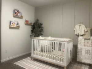 Carpeted bedroom with a crib and baseboards