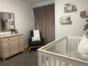 Bedroom featuring a crib and dark carpet