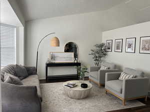 Living area with lofted ceiling, a textured ceiling, and wood finished floors