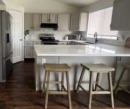 Kitchen with a peninsula, appliances with stainless steel finishes, a breakfast bar area, and light countertops