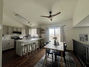 Dining area with dark wood-style floors, lofted ceiling, and ceiling fan