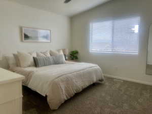 Bedroom featuring dark colored carpet, lofted ceiling, and baseboards