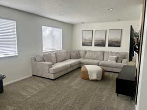 Carpeted living room featuring a textured ceiling and baseboards