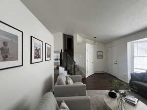 Living room with visible vents, lofted ceiling, stairway, wood finished floors, and a textured ceiling