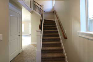 Stairway featuring carpet floors, a towering ceiling, and baseboards