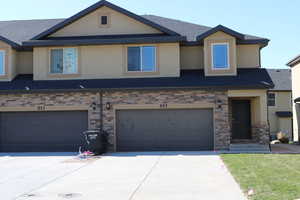 Townhome / multi-family property with a garage, concrete driveway, a shingled roof, and stucco siding