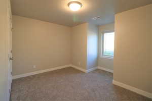 Spare room featuring baseboards, visible vents, and light colored carpet