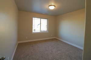 Spare room featuring carpet floors, visible vents, and baseboards