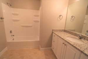 Full bathroom with washtub / shower combination, vanity, and baseboards