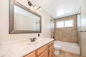 Bathroom with toilet, bathtub / shower combination, a textured ceiling, and vanity