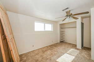 Unfurnished bedroom featuring a closet, light colored carpet, visible vents, a ceiling fan, and a textured ceiling