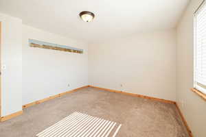 Unfurnished room with light carpet, a textured ceiling, and baseboards