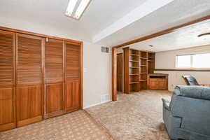 Living area featuring light carpet, visible vents, and a textured ceiling