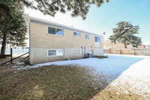 Back of house featuring brick siding, fence, and central air condition unit