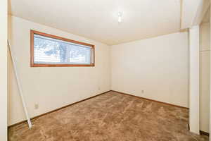 Spare room featuring carpet flooring, a textured ceiling, and baseboards