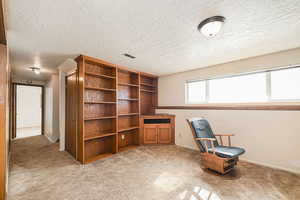 Sitting room featuring a textured ceiling, baseboards, visible vents, and light colored carpet