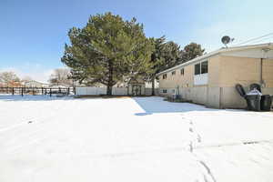 Snowy yard featuring a storage shed, fence, and an outdoor structure