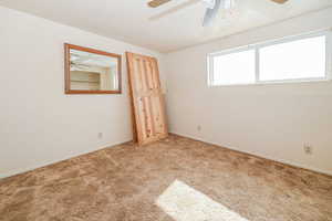 Unfurnished room featuring a ceiling fan, light colored carpet, and baseboards