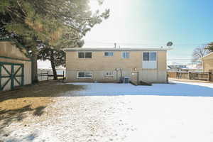 Snow covered rear of property featuring brick siding, a storage shed, fence, and an outdoor structure