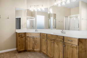 Bathroom featuring double vanity, a stall shower, a sink, and tile patterned floors