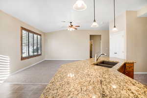 Kitchen featuring brown cabinets, decorative light fixtures, dark colored carpet, visible vents, and a sink