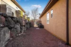 View of property exterior with central AC, fence, and stucco siding