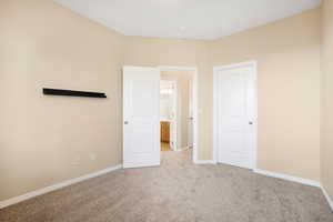 Unfurnished bedroom with baseboards and light colored carpet